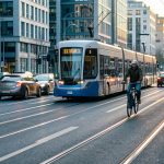 Scène urbaine moderne avec un tramway, un cycliste, un scooter et des piétons près de la route, avec des voitures en circulation.